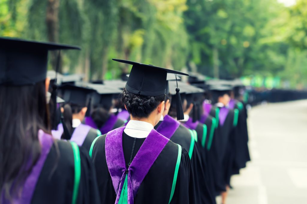 Back of graduates during commencement at university. Close up at graduate cap. Color tone image.