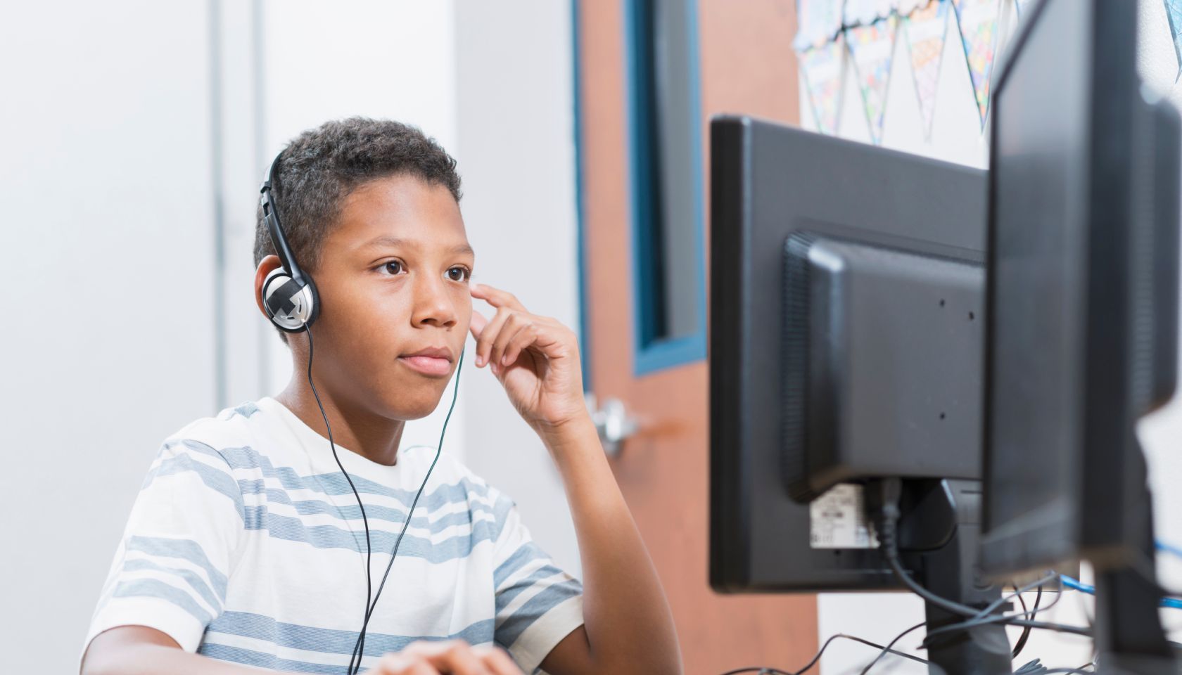 Boy in school using desktop computer wearing headphones