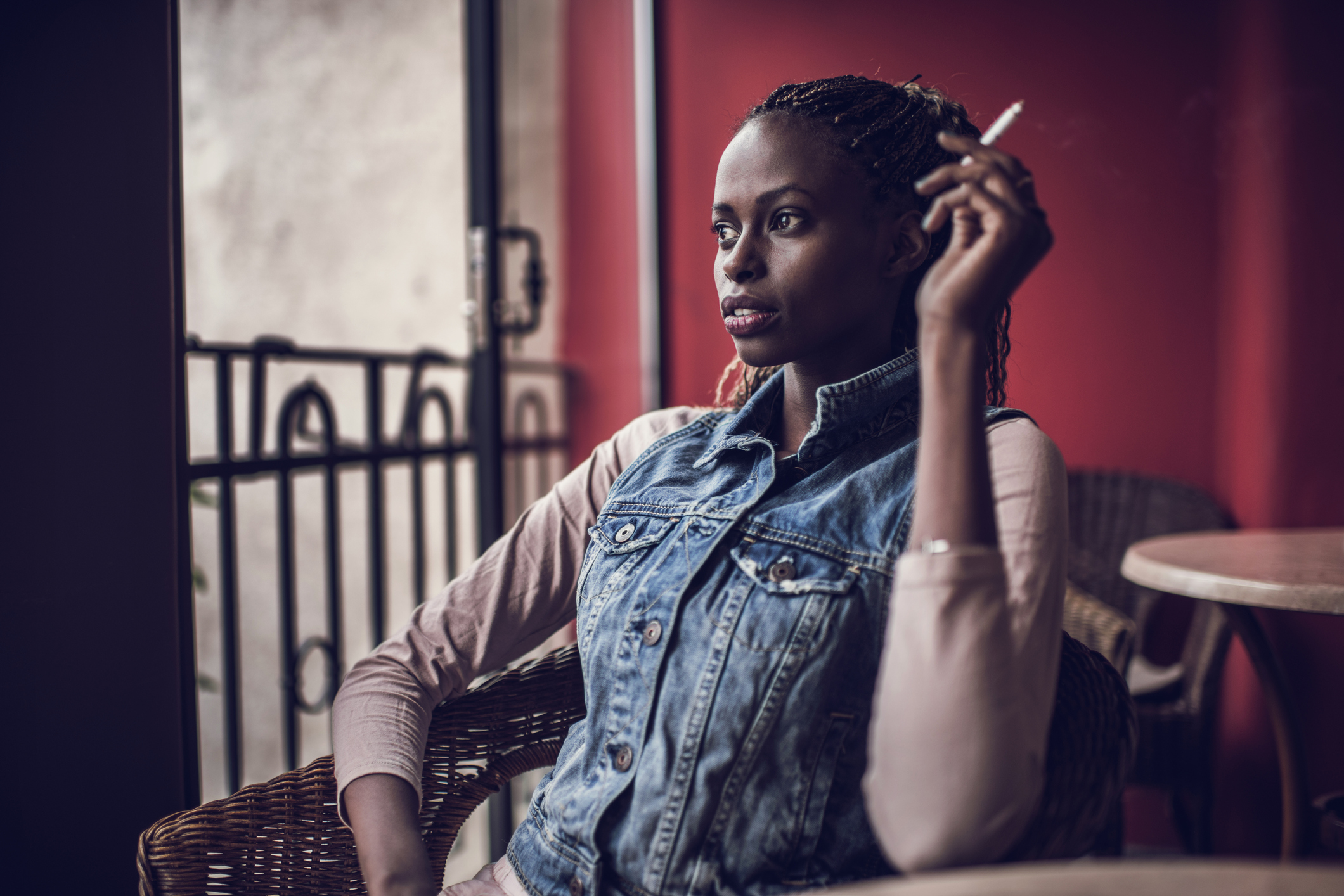 Young African American woman smoking a cigarette on a terrace.