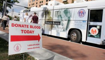 A donate blood sign in front of a Community Blood Centers bus