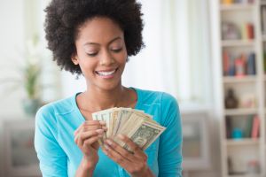 African American woman counting money in living room