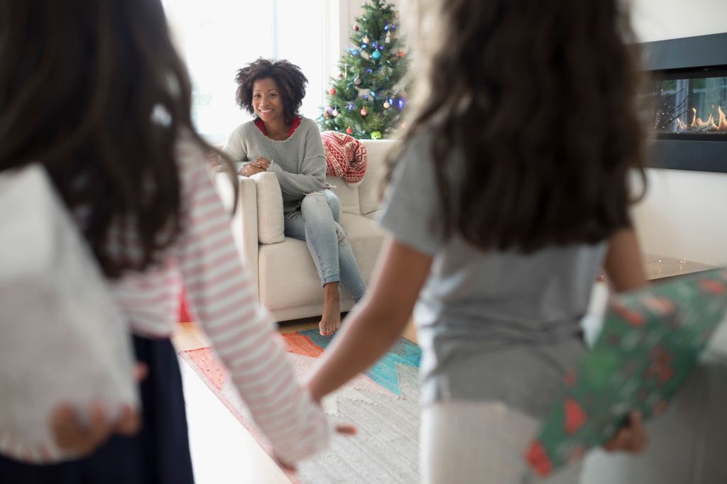 Daughters surprising mother with Christmas gifts in living room