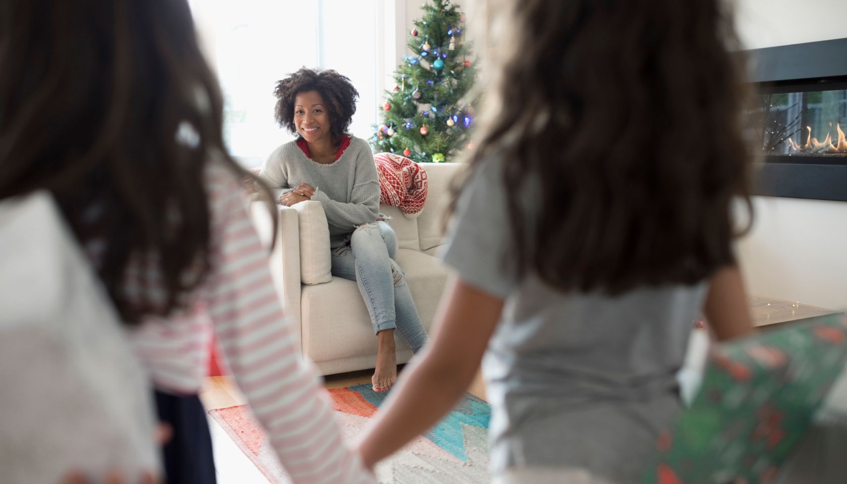 Daughters surprising mother with Christmas gifts in living room