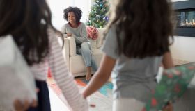 Daughters surprising mother with Christmas gifts in living room