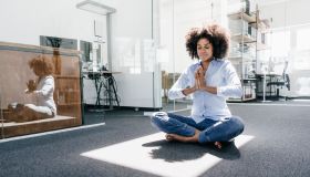 Young woman doing yoga in office