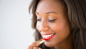 Black woman applying lipstick