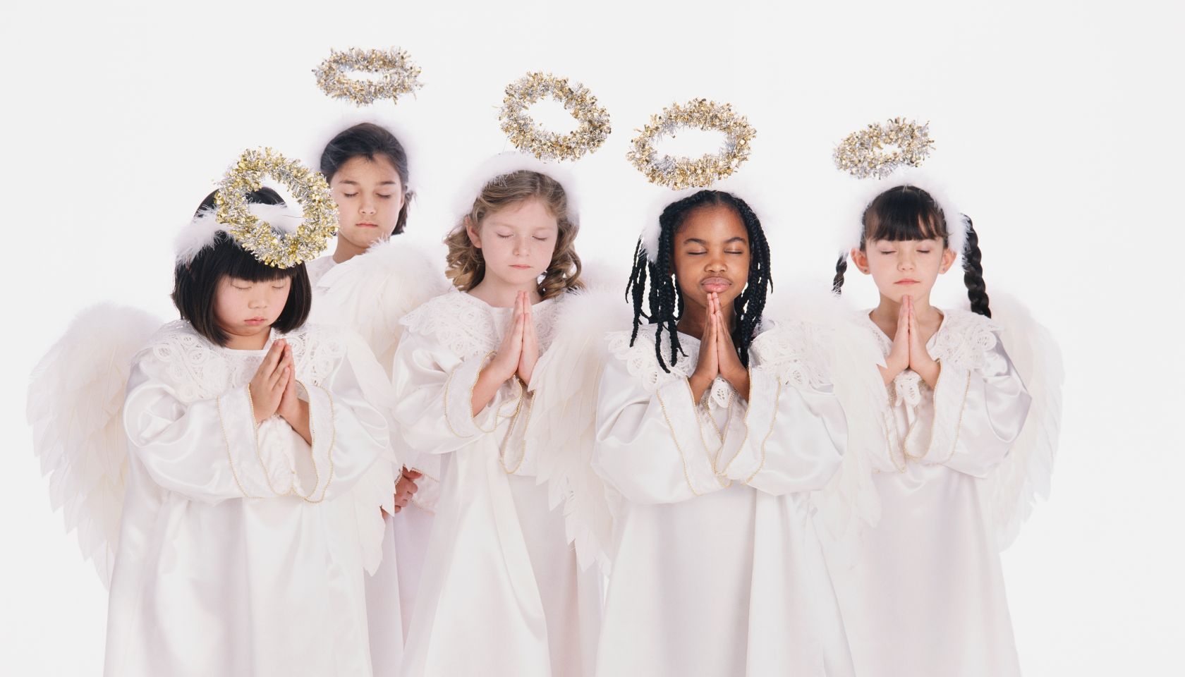 Diverse group of girls wearing angel costumes praying