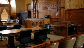 An empty, brown-paneled courtroom with flags
