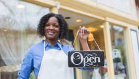 African American woman with apron holding an open sign