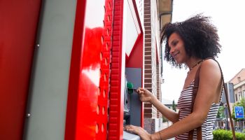 Smiling woman pushing credit card at cash dispenser