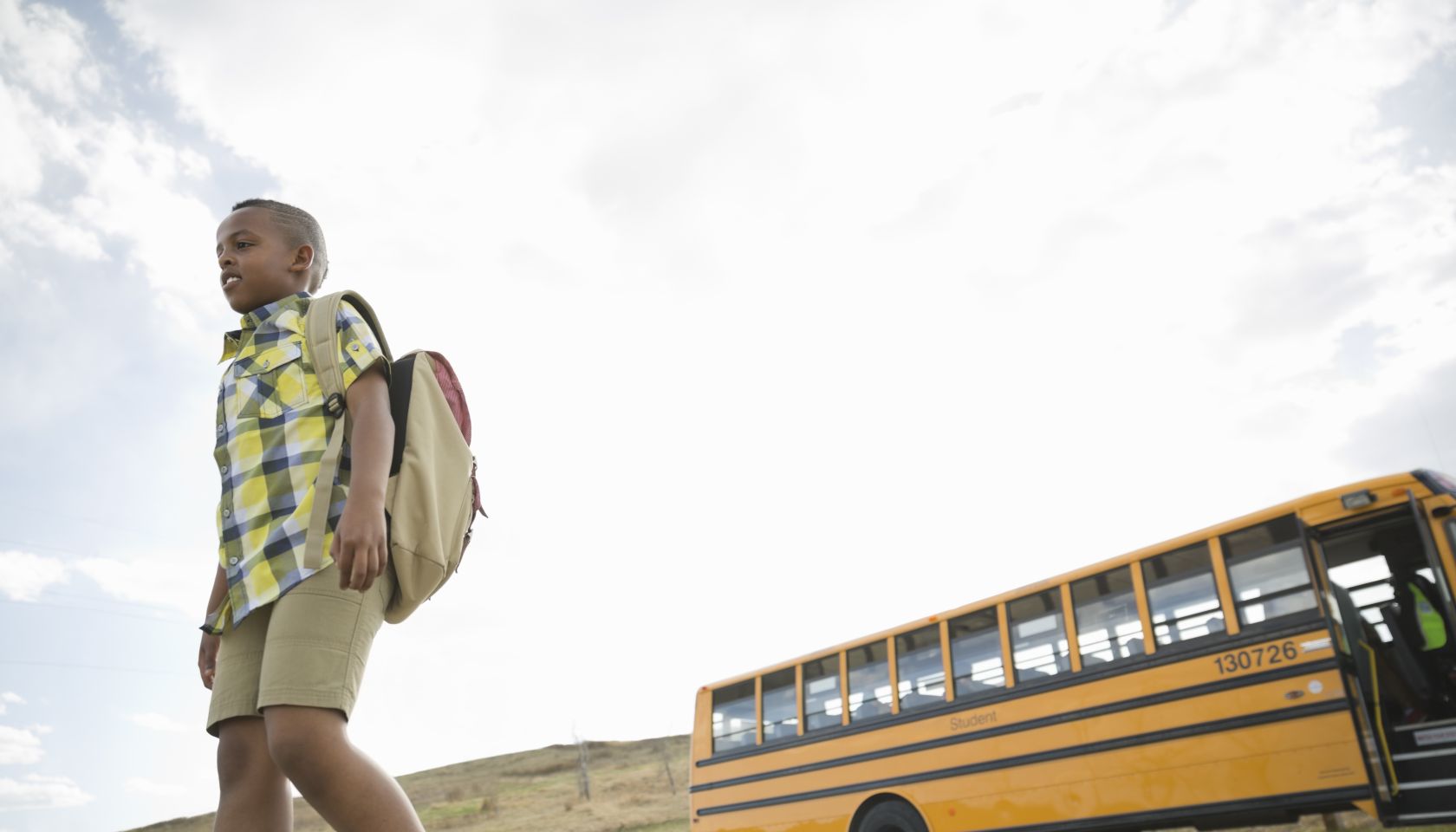 Low angle view of schoolboy walking away from school bus