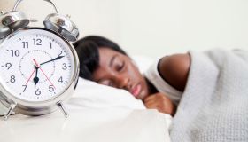 African teenaged girl sleeping, double bell alarm clock foregrounded, Cape Town, South Africa