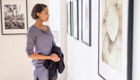 Black woman admiring paintings in art gallery