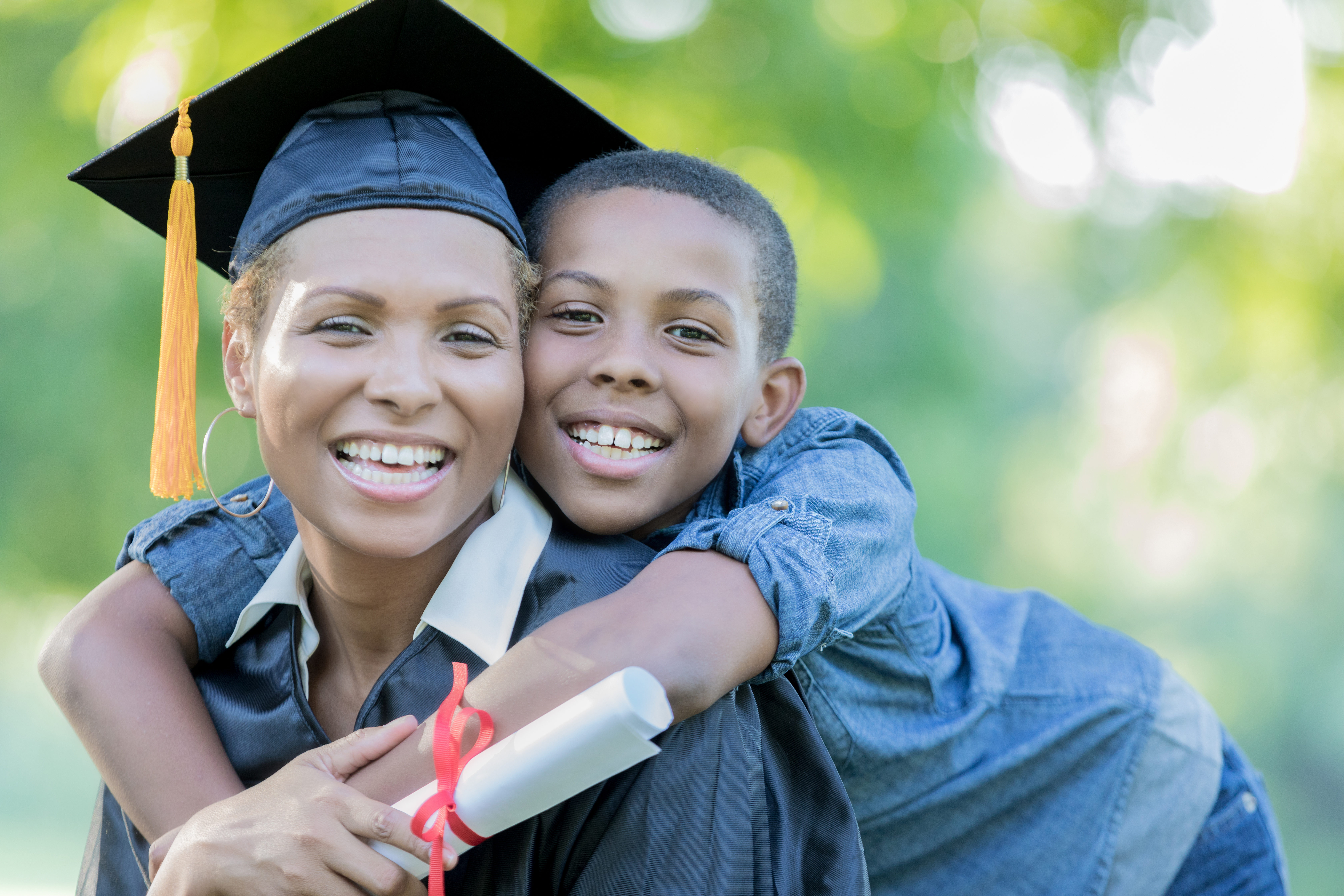 Tween son poses with mom after her college graduation ceremony