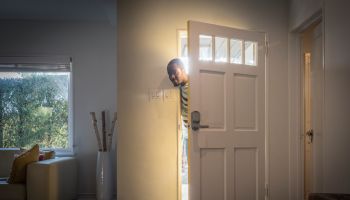Father arriving home peeping through open front door