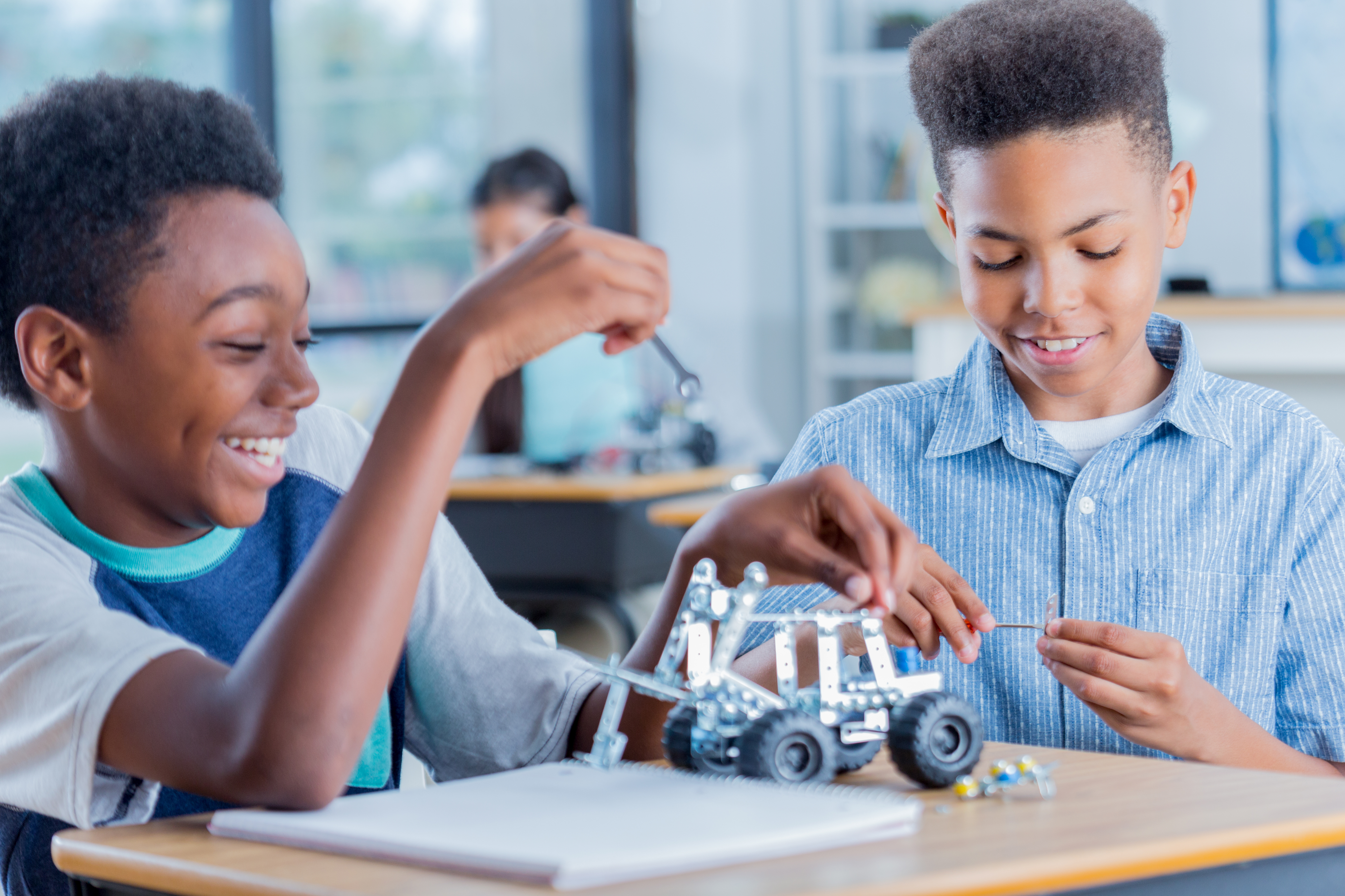 Two preteen boys work on robotics project together at school