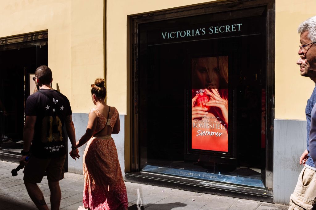 Tourists couple walking by Victoria´s Secret store in a...