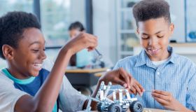 Two preteen boys work on robotics project together at school