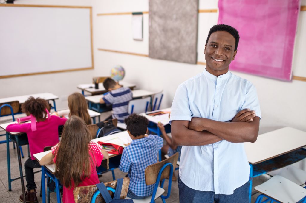 Smiling teacher standing arms crossed in classroom