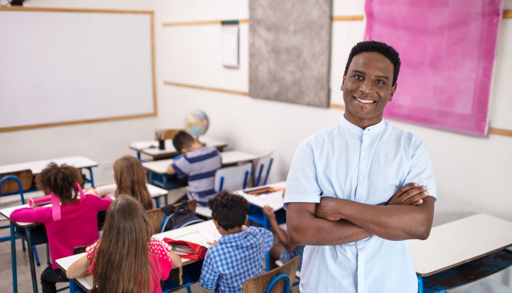 Smiling teacher standing arms crossed in classroom