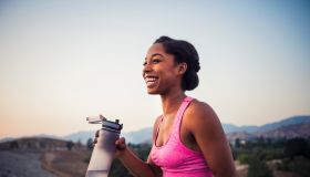 Happy female runner holding water bottle