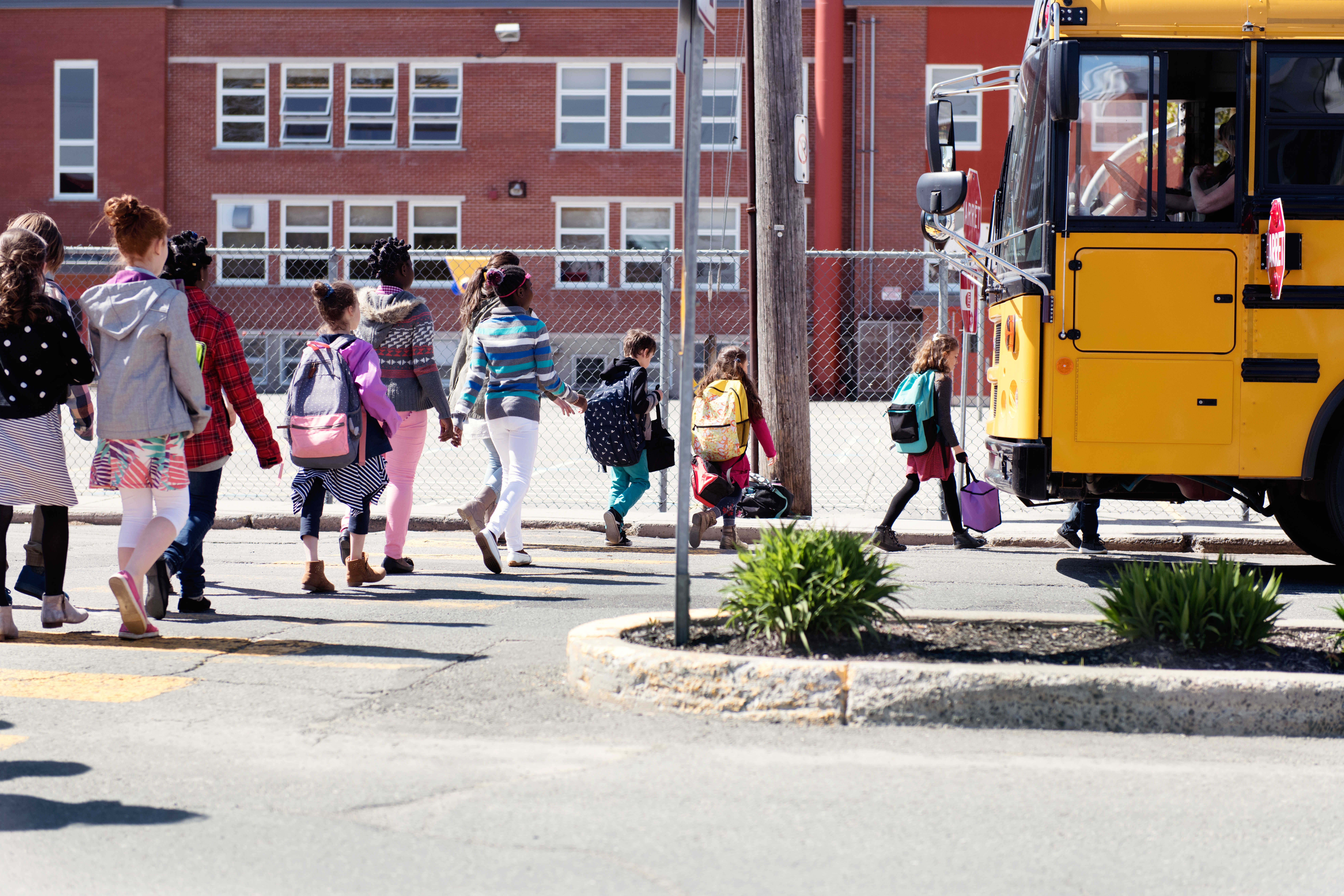 Multi-Ethnic Group of elementary school kids getting in a school bus at school's out.