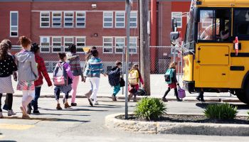 Multi-Ethnic Group of elementary school kids getting in a school bus at school's out.