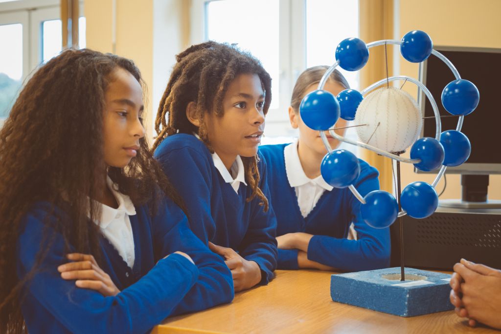 Schoolchildren examining molecular structures in classroom