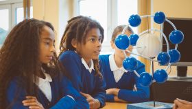 Schoolchildren examining molecular structures in classroom