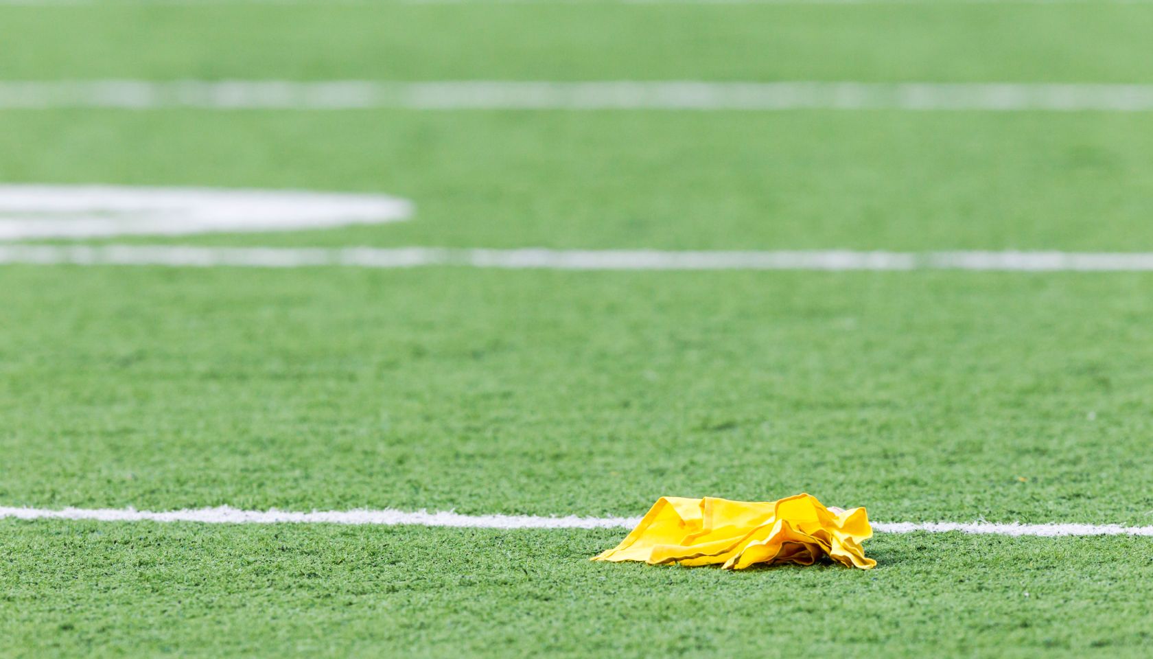 Penalty flag laying on American football field