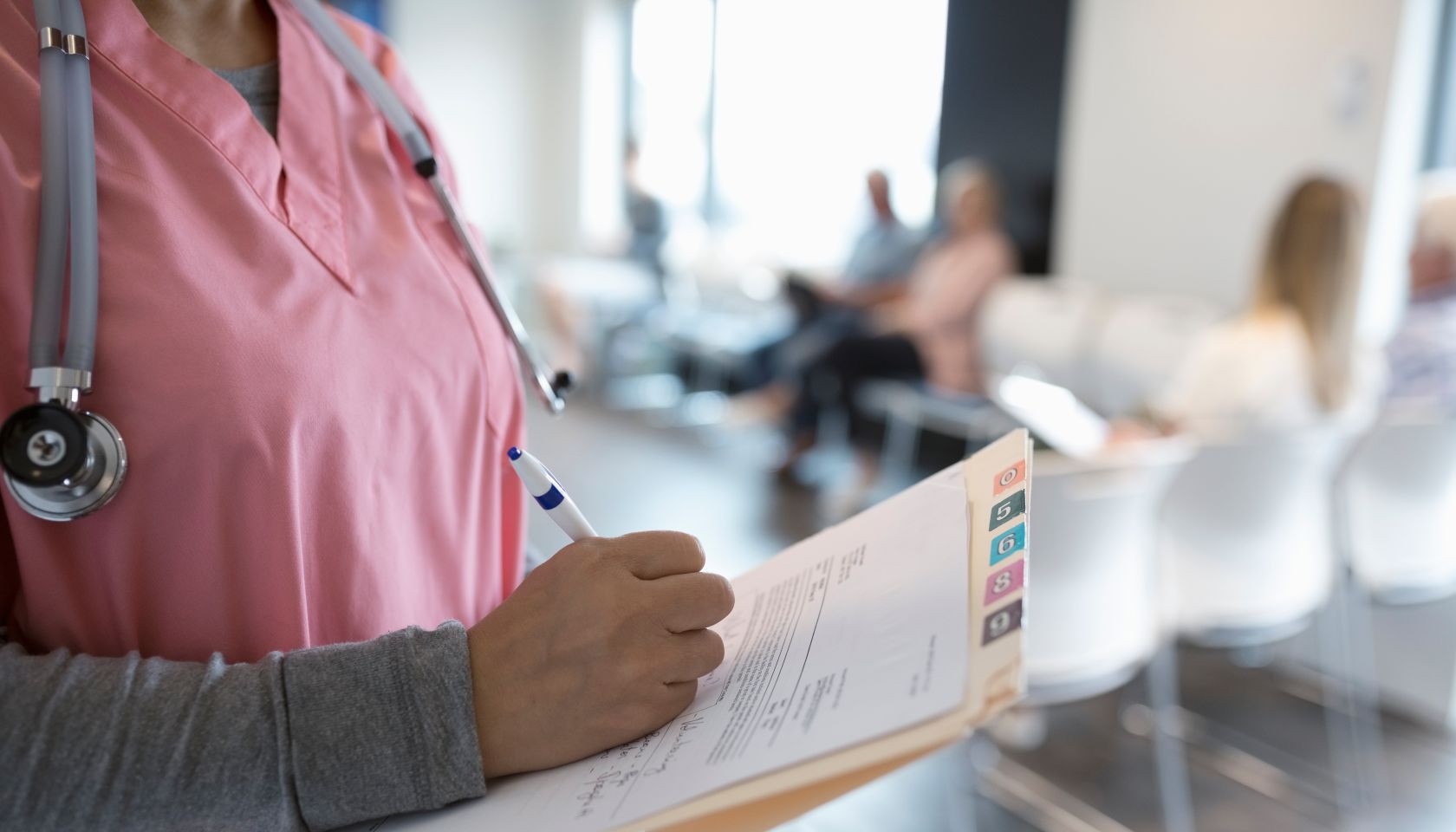 Close up female nurse writing on medical record in clinic waiting room
