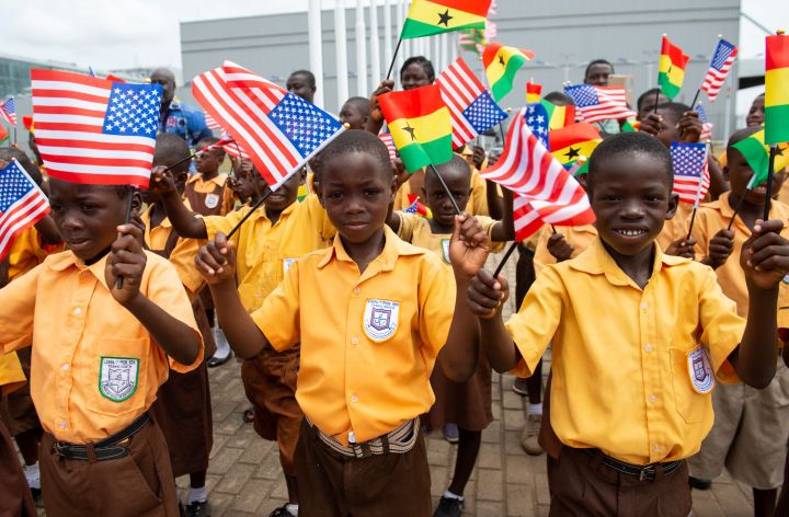 Children wave the American and Ghana flags