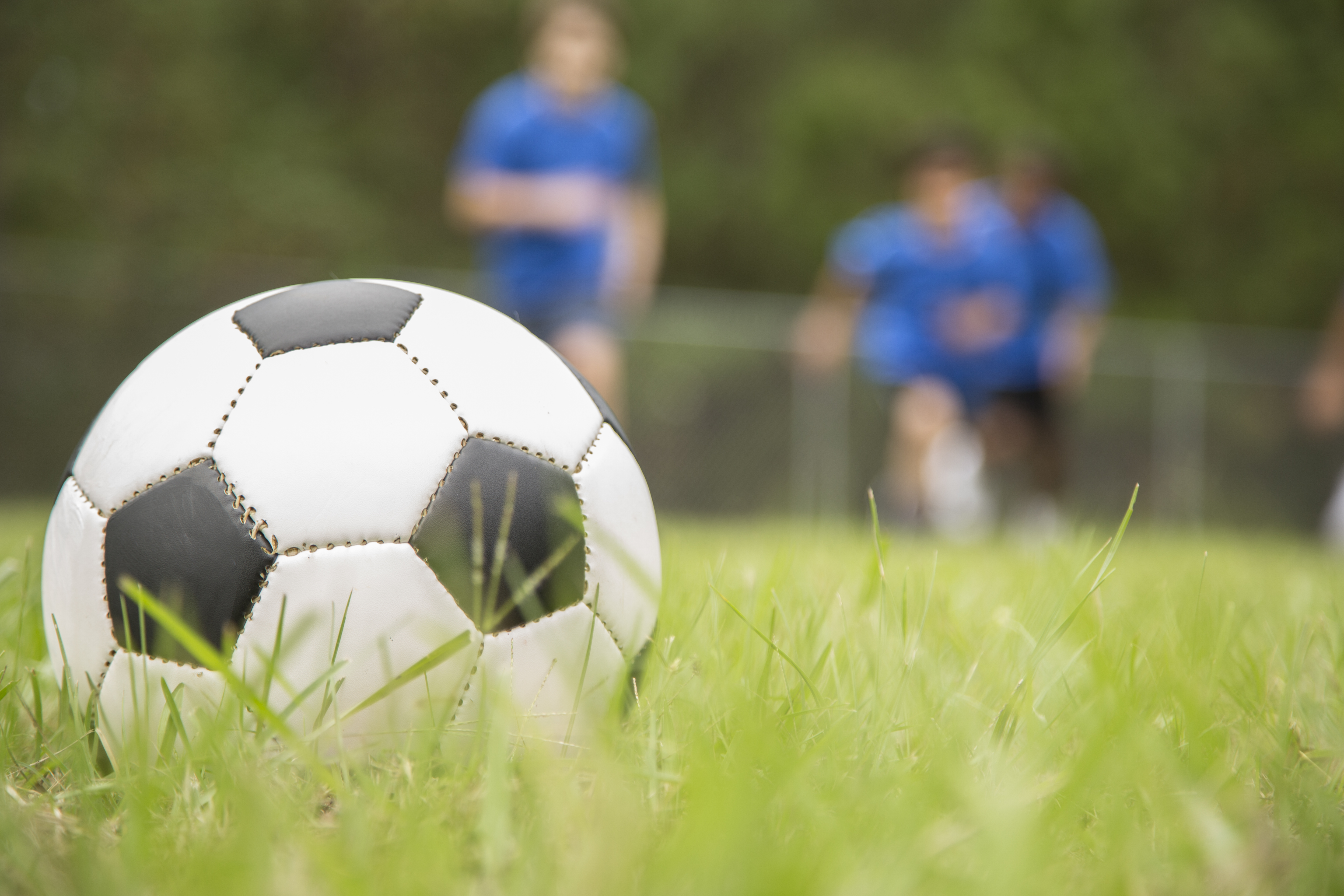 Children's soccer team players run toward ball on playing field.