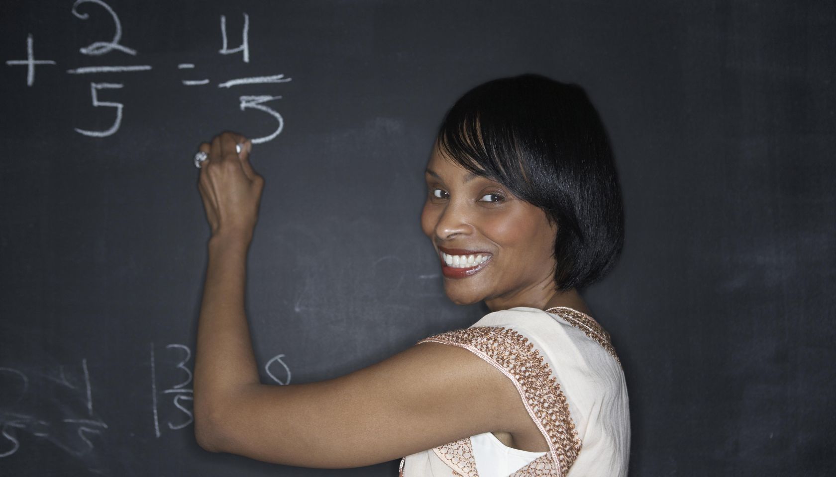 Teacher writing with chalk on a blackboard.