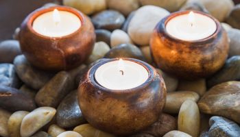 Close-up of lit tea light candles in dish of stones