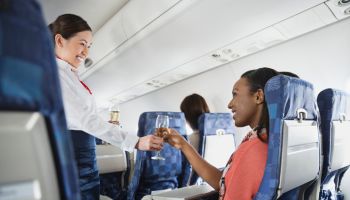 Flight attendant serving champagne to passenger