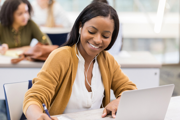 Young female college student enjoys studying to music in library