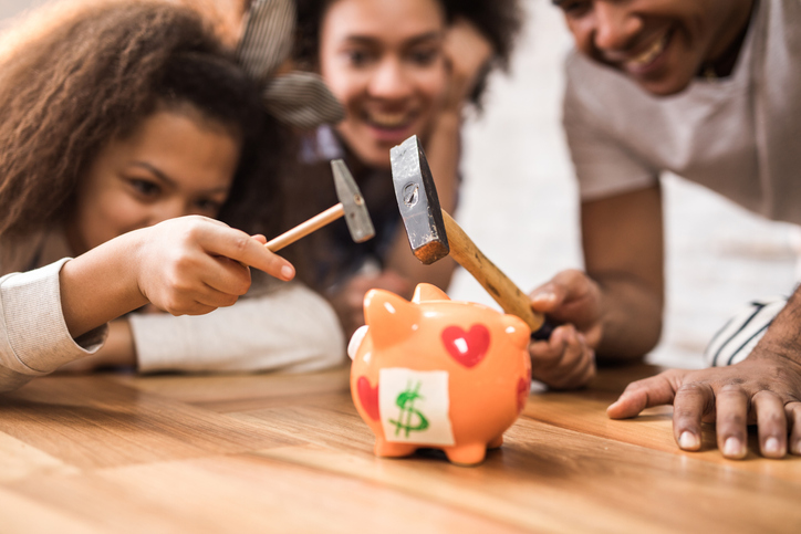 Close up of a black family cracking a piggy bank.