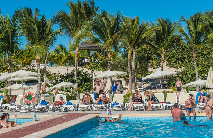 Adults relaxing in and around the swimming pool at a resort
