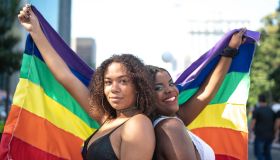 Portrait of friends waving rainbow flag during Pride Parade