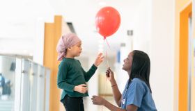 Doctor gives a red balloon to a little girl with cancer