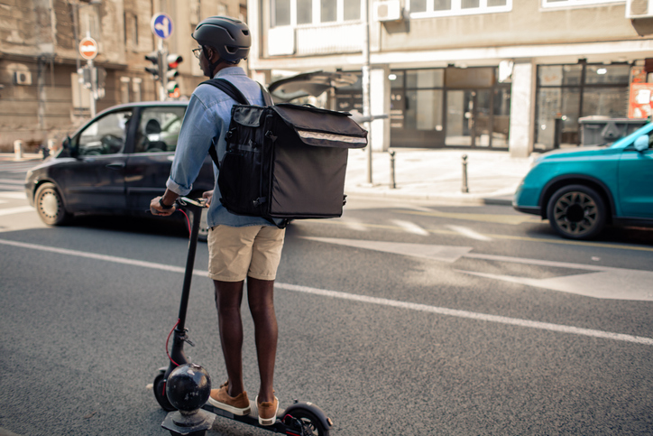 Young African Delivery Man Riding Electric Scooter In the City