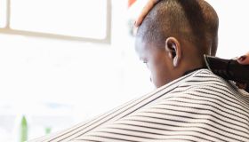Hairdresser clipping hair of boy in retro barbershop