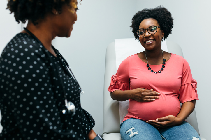 Black doctor talking with third trimester pregnant woman