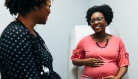 Black doctor talking with third trimester pregnant woman