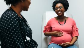 Black doctor talking with third trimester pregnant woman