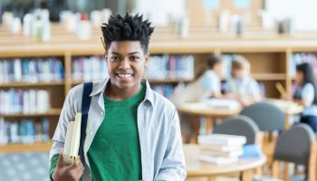 Confident teenage boy checks books out from the library