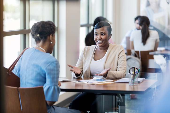 Mid adult banker helps mature adult woman understand her options