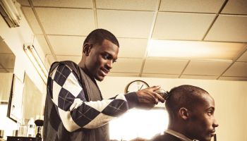 Barber in traditional barber shop shaving man's head