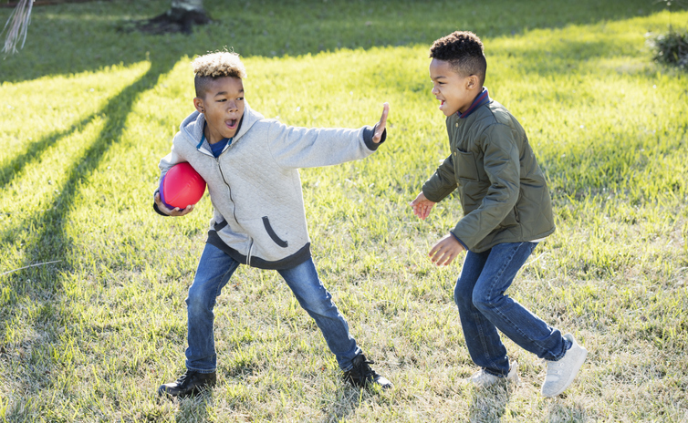 Two boys playing football in back yard